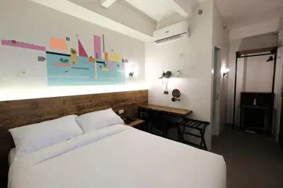a bedroom with a white bed and a desk with a desk at U Hotels Makati in Manila
