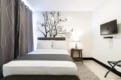 a bedroom with a bed and a tv on a wall at Artemis Place Makati Hotel in Manila