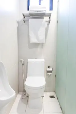 a bathroom with a toilet and a sink and towels at Artemis Place Makati Hotel in Manila