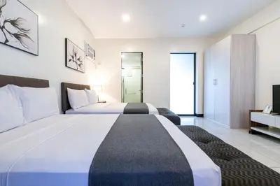 a large bedroom with two beds and a tv at Artemis Place Makati Hotel in Manila
