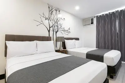 two beds in a hotel room with white and black at Artemis Place Makati Hotel in Manila