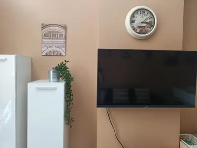 a clock and a flat screen tv next to a refrigerator at Shell Residences in Manila