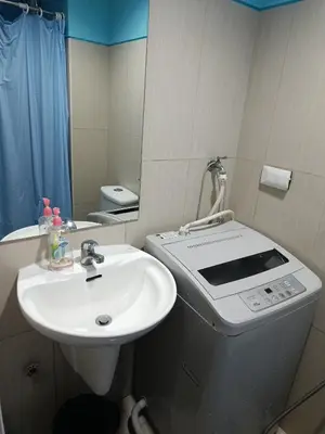 a bathroom with a sink and a washing machine at Shell Residences in Manila