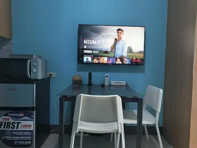 a dining room table with chairs and a tv on the wall at Shell Residences in Manila