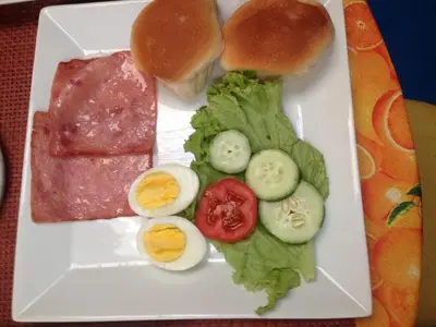 a plate of food with ham eggs and vegetables at Casa Joaquin BnB in Manila