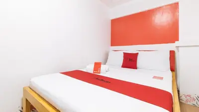 a bedroom with a white bed with red accents at RedDoorz at DBuilders Rooms Ph1 Taguig in Manila