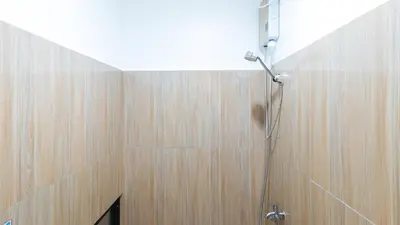 a shower in a bathroom with a wooden wall at RedDoorz at DBuilders Rooms Ph1 Taguig in Manila