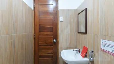 a bathroom with a sink and a wooden door at RedDoorz at DBuilders Rooms Ph1 Taguig in Manila