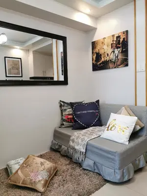 a bedroom with a bed and a couch and a mirror at Reese @ Sea Residences Manila in Manila