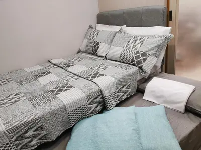 a bed with a gray and white comforter and pillows at Reese @ Sea Residences Manila in Manila