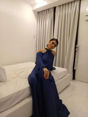 a woman in a blue dress sitting on a bed at Penthouse suite at Porto Vita Towers in Cubao Quezon City in Manila