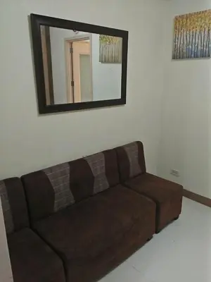 a brown couch in a living room with a mirror at CHATEAU ELYSSE a4 near SM Mall,AIRPORT Wifi in Manila