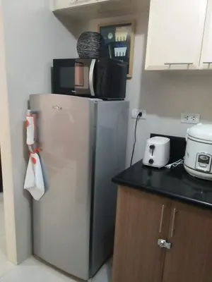 a kitchen with a refrigerator with a microwave on it at Condo Apartment near Manila Airport NAIA T3 in Manila