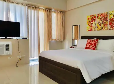 a bedroom with a large bed and a television at Condo Apartment near Manila Airport NAIA T3 in Manila