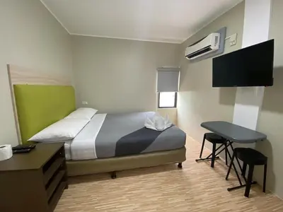 a bedroom with a bed and a table and a desk at DG Budget Hotel Salem in Manila
