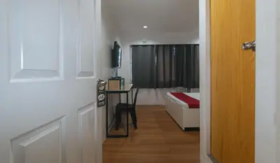 a hallway with a room with a bed and a television at RedDoorz Plus at Boni Avenue Mandaluyong in Manila
