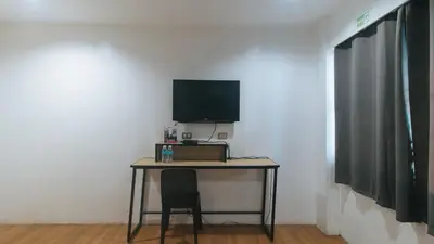 a desk with a television and a chair in a room at RedDoorz Plus at Boni Avenue Mandaluyong in Manila