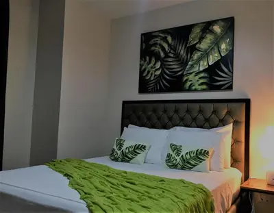 a bedroom with a bed with green sheets and pillows at Travellers 101 Condo near Manila Airport in Manila