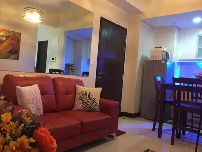 a living room with a brown couch and a kitchen at Travellers 101 Condo near Manila Airport in Manila