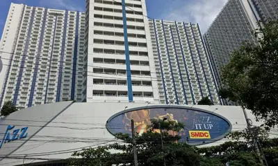 a tall building with a sign in front of it at Jazz Residences Condo in Manila