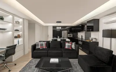 a living room with a black couch and a kitchen at The Alpha Suites in Manila