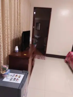 a living room with a desk and a television at Lourdes Inn in Manila