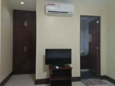 a living room with a television and a wall with a air conditioner at Lourdes Inn in Manila