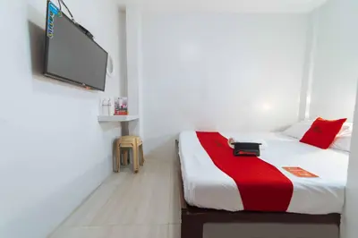 a bedroom with a bed with a tv on the wall at RedDoorz at San Antonio Binan Laguna in Biñan