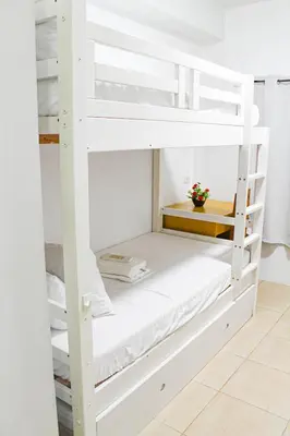 a bunk bed room with white bunk beds at Titan Condo at Studio City Tower 3 Alabang in Manila