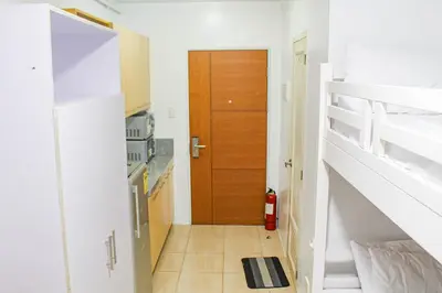 a hallway with a wooden door and a staircase at Titan Condo at Studio City Tower 3 Alabang in Manila