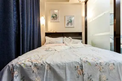 a bedroom with a bed with a blue curtain at Jen's Paranaque City Apartment in Manila