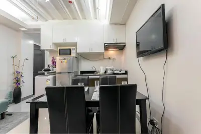 a kitchen with a dining table and a flat screen tv at Jen's Paranaque City Apartment in Manila