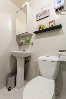 a white bathroom with a toilet and a sink at Jen's Paranaque City Apartment in Manila