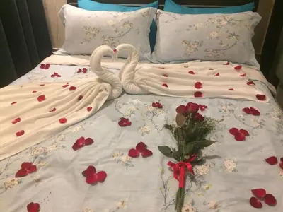 two white swans laying on a bed with flowers at Jen's Paranaque City Apartment in Manila