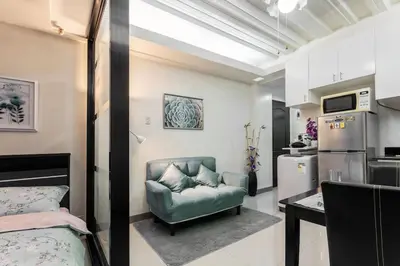 a living room with a green couch and a kitchen at Jen's Paranaque City Apartment in Manila