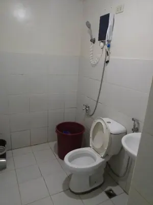 a bathroom with a toilet and a phone on the wall at Vimelzu Mhavic Family Room in Manila