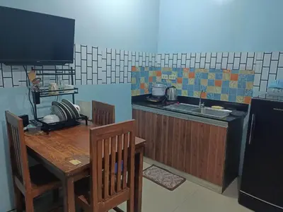 a kitchen with a wooden table and a counter with a sink at Vimelzu Mhavic Family Room in Manila