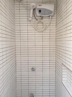 a shower in a bathroom with white tiles at 1 River Central Hostel in Manila
