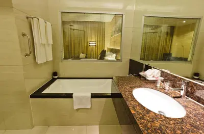 a bathroom with a tub and a sink and a mirror at Ramada by Wyndham Manila Central in Manila