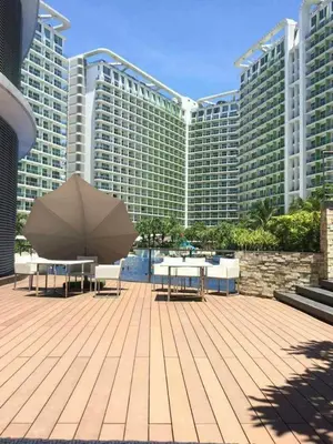 a patio with tables and an umbrella in front of a large building at Azure Urban Resort Maui Unit in Manila