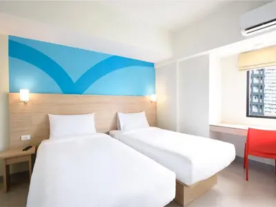 a bedroom with two beds and a red chair at Hop Inn Hotel Alabang Manila in Manila