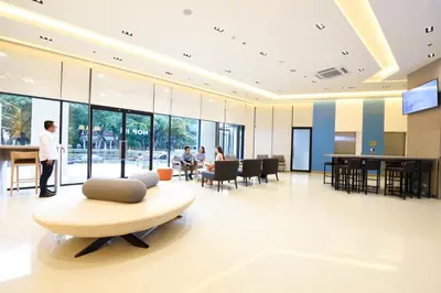 a lobby with a chair and a table and people at Hop Inn Hotel Alabang Manila in Manila