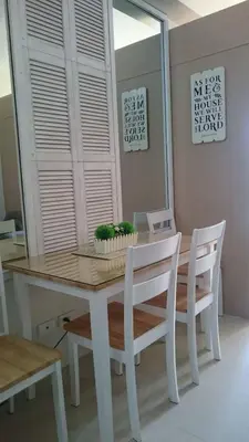 a dining room table with white chairs and a table and a mirror at Genesis unit SMDC Fields in Manila