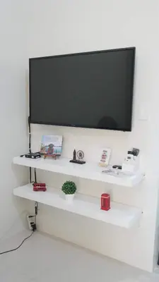a flat screen tv on a wall with white shelves at Genesis unit SMDC Fields in Manila