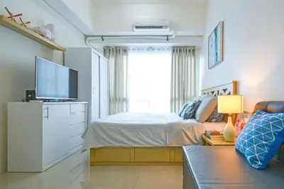 a bedroom with a bed and a tv and a couch at Amora Suites at the Beacon Makati in Manila