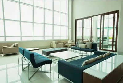 a lobby with blue couches and tables and windows at Amora Suites at the Beacon Makati in Manila
