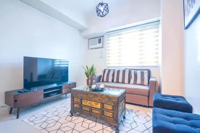 a living room with a couch and a flat screen tv at Amora Suites at the Beacon Makati in Manila