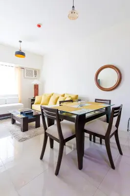 a living room with a table and chairs and a couch at Amora Suites at the Beacon Makati in Manila