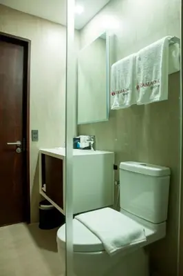 a bathroom with a toilet and a sink and a mirror at Ramada Encore by Wyndham Makati in Manila