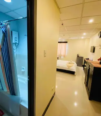 a room with a bed and a bathroom with a tub at Amax Inn Makati in Manila